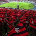 Estádio Maracanã com troféu da Copa Libertadores e bandeiras do Flamengo, celebrando a conquista do tetra em 2025.