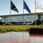 Bandeiras do Brasil, UE e Mercosul no Palácio do Planalto, simbolizando compromisso com acordo comercial em carta a Lula.