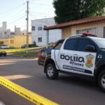 Cena de crime isolada por fita policial em rua residencial de Goiânia, com viatura da PM ao lado.