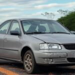 Acidente de carro na BR-153 em Goiás, veículo danificado na rodovia, paisagem rural do cerrado, sem pessoas.
