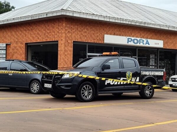 Fachada de supermercado em Iporá, Goiás, com fita de isolamento policial e viatura da PM, representando cena de crime sem pessoas.