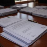 Mesa com documentos oficiais em gabinete governamental brasileiro, representando assinatura de MP para reajuste salarial de professores.