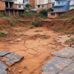 Residências desabadas por erosão do solo em área urbana de Goiânia, com destroços e terra rachada.