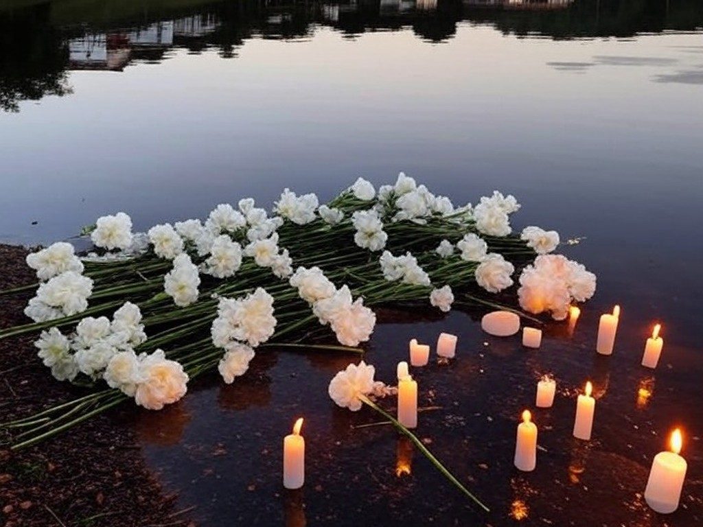 Memorial simbólico com flores e velas à beira do Lago dos Tigres em Britânia, Goiás, homenageando vítima de assassinato.