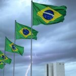 Foto de raio atingindo manifestação em Brasília, com bandeiras verde-amarelas e Congresso Nacional ao fundo.