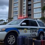 Viatura da polícia em frente a condomínio em Caldas Novas com malas abandonadas, representando prisão por investigação de morte.