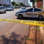 Rua em Águas Claras com fita de isolamento policial e viatura da PMDF, representando incidente de violência envolvendo piloto.