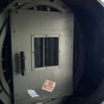 Cofre de banco aberto com poucas notas de real, representando baixa reserva antes de liquidação no Brasil.