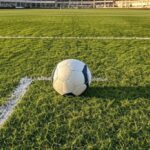 Campo de futebol em Goiânia com bola solitária, representando individualidade no esporte pelo Atlético-GO.