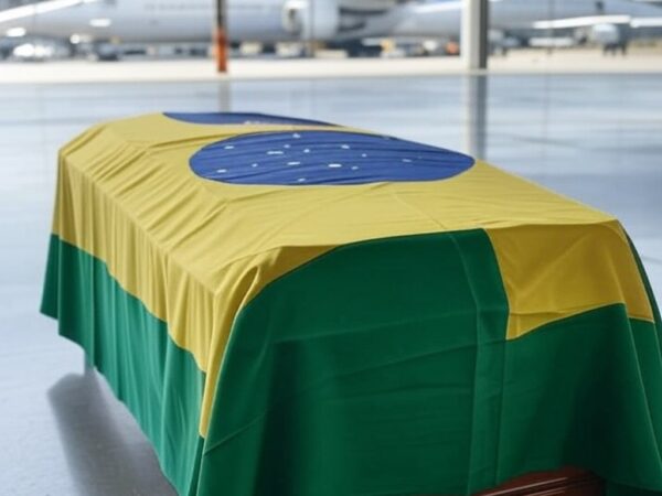Caixão com bandeira brasileira em aeroporto, representando translado de corpo de brasileiro morto em Paris por complicações estomacais.