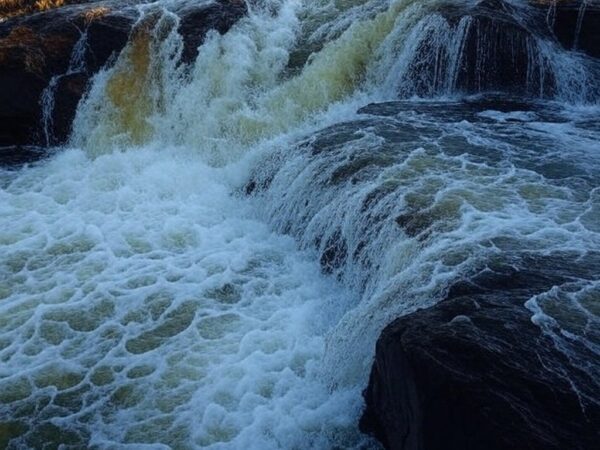 Cachoeira em Aragoiânia, Goiás, com águas correndo sobre rochas, local de afogamento de jovem colombiano.