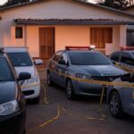 Casa em Itumbiara isolada por fita policial, com viaturas da PM, representando cena de tragédia doméstica.