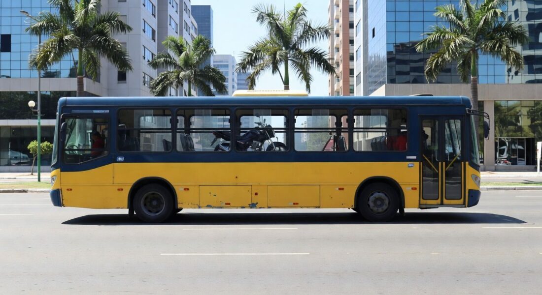 Ônibus urbano em Goiânia transportando moto no interior, cena de rua com arquitetura local.