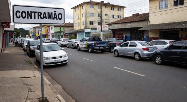 Rua em Anápolis com placa de contramão e viatura policial, representando incidente de agressão após direção irregular.