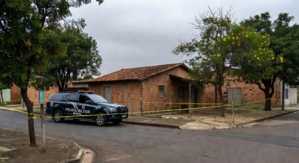 Viatura da Polícia Militar em rua de Goiânia, com fita de isolamento em cena de feminicídio.