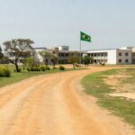 Campo de treinamento vazio do Exército em Goiânia, com pista de corrida e quartel ao fundo.